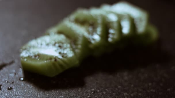 Suculentas fatias de frutas kiwi frescas em uma placa de corte de mármore preto. Vista macro. Movimento lento — Vídeo de Stock