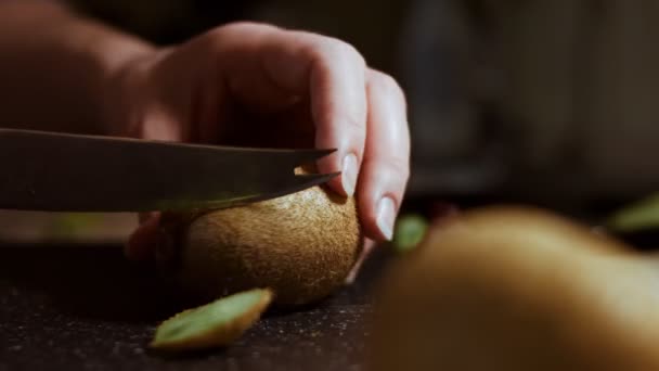 Pelando un jugoso kiwi verde sobre una tabla de cortar de mármol negro. Cronograma — Vídeo de stock