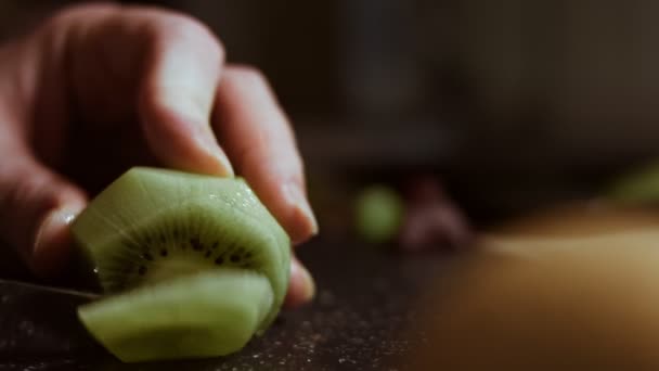 Trancher un kiwi vert juteux sur une planche à découper en marbre noir. Vue macro — Video