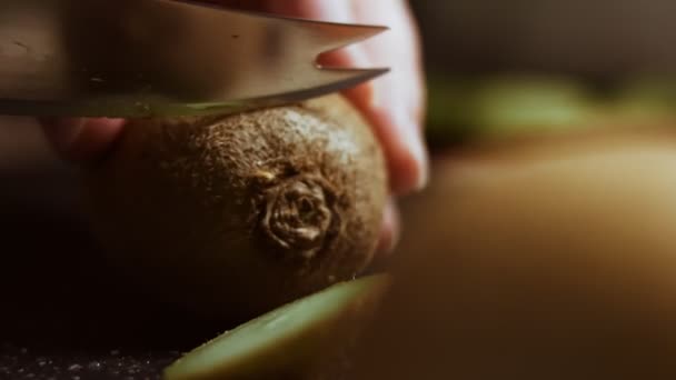 Eine saftige grüne Kiwi auf einem schwarzen Marmorschneidebrett schälen. Makrosicht — Stockvideo