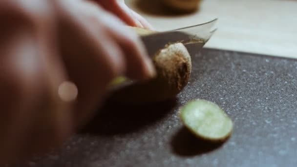 Pelando un jugoso kiwi verde sobre una tabla de cortar de mármol negro. Vista macro — Vídeos de Stock