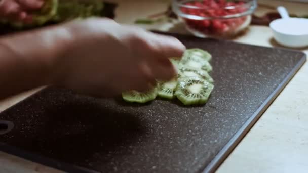 Sappige verse kiwi 's en rode bessen in de vorm van een kerstboom op een zwart marmeren snijplank. Eten voor kerstvakantie. Een gezonde snack. Tijdsverloop — Stockvideo