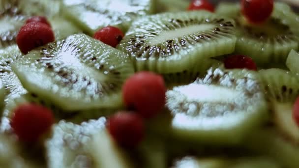 Jugosos trozos de kiwi fresco y grosella roja congelada dispuestos en forma de árbol de Navidad en una tabla de cortar de mármol negro. Comida para las vacaciones de Navidad. Un bocadillo saludable. Vista macro. Lento. — Vídeo de stock