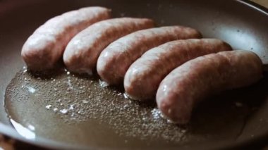 Siyah tavada yağlı sosis pişirin. Sıcak ayçiçeği yağında kızarmış sosis..