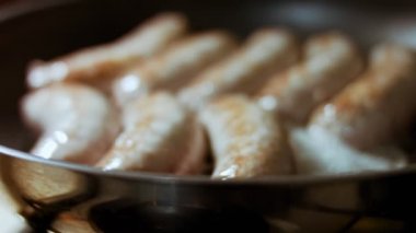 Siyah tavada yağlı sosis pişirin. Sıcak ayçiçeği yağında kızarmış sosis. Sıcak buharlar sosislerden buharlaşıyor..