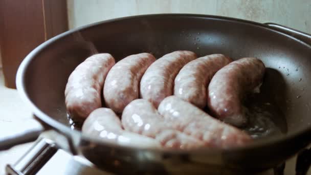 Close-up de salsichas de cozinha em panela preta com óleo. Salsichas de fritura em óleo de girassol quente. Vapores quentes a evaporar das salsichas. Movimento lento — Vídeo de Stock