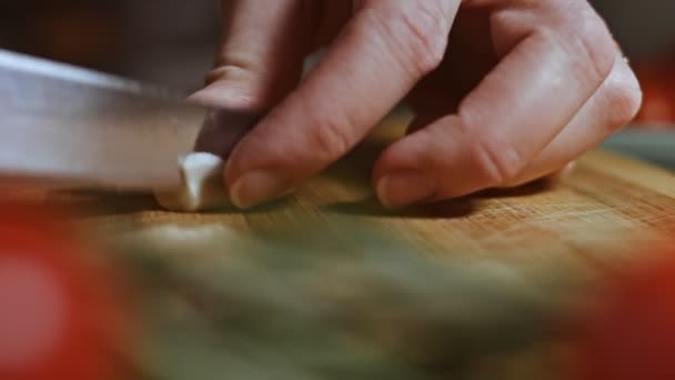 Cut garlic with a knife. Woman cuts the cloves of garlic on small pieces. Nice decoration. — Stockvideo