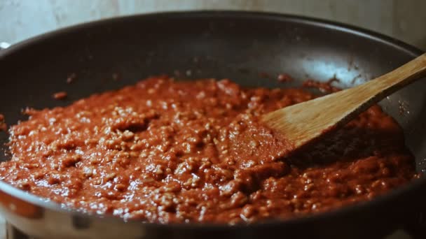 Într-o tigaie cu ulei vegetal prăjiți carne tocată, ceapă și morcovi cu pastă de roșii. Sosul Bolognese. legume prăjite pentru supe, presărați cu busuioc. Home bucatarie — Videoclip de stoc