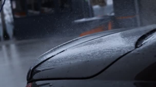 Biltvätt process av lyxbil full med vitt skum och stänk från vattenpistol. Spridning av skum på glänsande bil exteriör. Fin stämning. 4K-video — Stockvideo