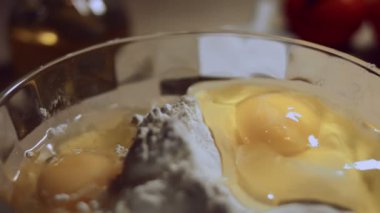 Undan elde edilen hamur işlemini kapat. Tavuk yumurtası ve cam kasede bir yığın beyaz un. Ravioli hazırlama işlemi. 4K video. Yavaş çekim