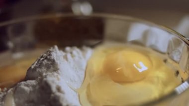 Undan elde edilen hamur işlemini kapat. Tavuk yumurtası ve cam kasede bir yığın beyaz un. Ravioli hazırlama işlemi. 4K video. Yavaş çekim