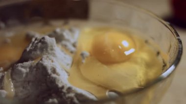 Undan elde edilen hamur işlemini kapat. Tavuk yumurtası, zeytinyağı ve cam kasede bir yığın beyaz un. Ravioli hazırlama işlemi. 4K video. Yavaş çekim