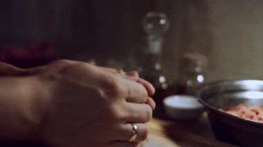 Kadın hamuru tahtanın üzerine yuvarlıyor. Kadın eli merdaneyle hamuru yuvarlıyor, yakın plan. Evde ravioli hazırlama süreci. 4K video