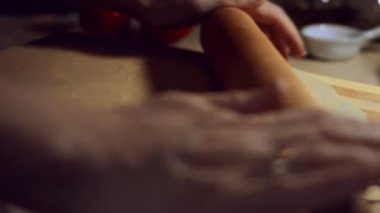 Kadın elleri hamuru tahtanın üzerine yuvarlıyor. Kadın eli merdaneyle hamuru yuvarlıyor, yakın plan. Evde ravioli hazırlama süreci. 4K video