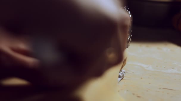 Kadın eli ahşap bir tahtanın kenarlarını kesmek için ravioli jant kesicisi kullanıyor. Evde ravioli hazırlama süreci. 4K video, yakın plan. — Stok video