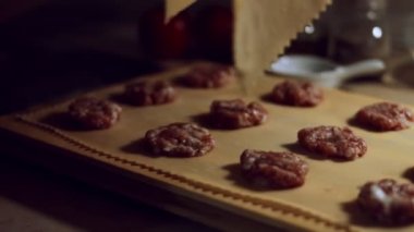 Eti hamurla kaplayan kadın eli yakın plan. Tipik bir İtalyan yemeği olan ravioli hazırlamak, eski İtalyan geleneğine göre ev yapımı. 4K video.
