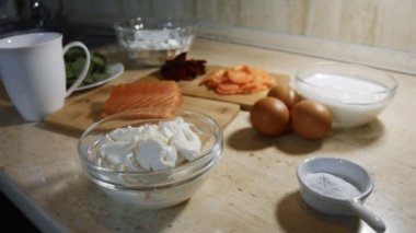 İnce, renkli krepler. Krem peynirli ve somon dolgulu kırmızı, sarı ve yeşil krep hazırlamak için malzemelerin yakın çekimi. 4K video.