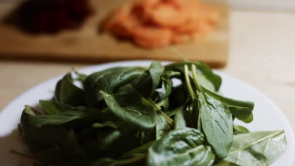 Hojas frescas de espinaca colocadas en un plato blanco. Concepto de comida saludable. Vídeo 4K — Vídeo de stock