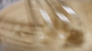 Taze yumurta, un ve sütü cam bir kasede çelik elle karıştırmanın makro görüntüsü. Krep hazırlama süreci. 4K video