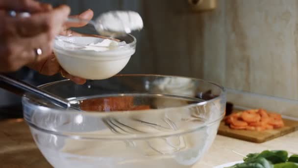 Mescolare uova fresche, farina e latte con miscelatore manuale in acciaio in una ciotola di vetro. Aggiungendo panna acida. Processo di preparazione dei pancake. Video 4K — Video Stock