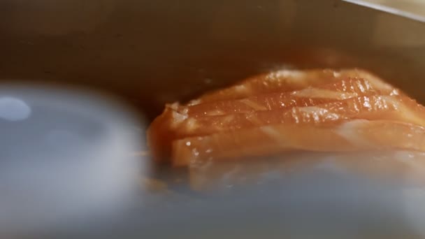 Gros plan d'une femelle tranchant du filet de saumon frais à la main sur une planche de bois. Vidéo 4K, macro — Video