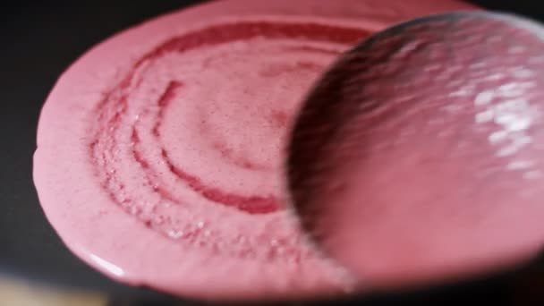 Étendre la pâte à crêpes rouges en rond se déplace dans une casserole pour la cuisson des crêpes. Processus de préparation de crêpes colorées. Vidéo 4K — Video