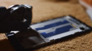 Bir yüzeyde duran akıllı telefon ekranının makro görüntüsü. Deli biri sert bir objeyle perdeyi kırıp sertçe vuruyor. Bozuk akıllı telefon. 4K video