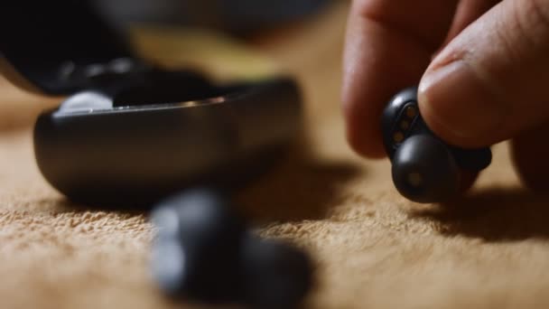 Close-up of wireless earphones in the charging case. Males hand puting the earphones into case and then closing the case. 4K video — Stockvideo