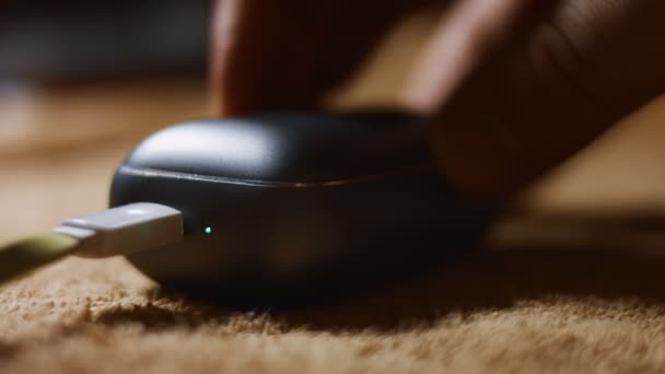 Close-up of wireless earphones in the charging case. Process of charging of the modern earphones. Male hand taking an earphone from case to check it. 4K video — Stockvideo