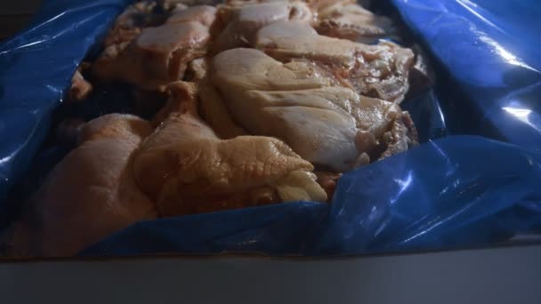 Donmuş tavuk bacaklarıyla dolu bir kutunun yakından görüntüsü. Buzla kaplı donmuş çiğ tavuk eti. 4k video — Stok video