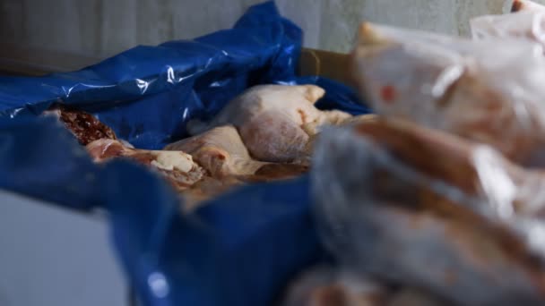 冷凍鶏の足を持つボックスに投げられている中古手袋のペアのクローズアップビュー。家庭でのさらなる使用のための梱包と冷凍鶏の肉のプロセス。4Kビデオ — ストック動画