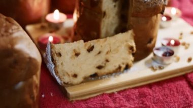 Milan 'ın leziz Panettone' unun tepesinde mum dolu güzel bir atmosferde pudra şekeri. Noel için geleneksel İtalyan hamur işleri ve kurutulmuş meyveler. Panettone dilimi yakından görülüyor. 4K video