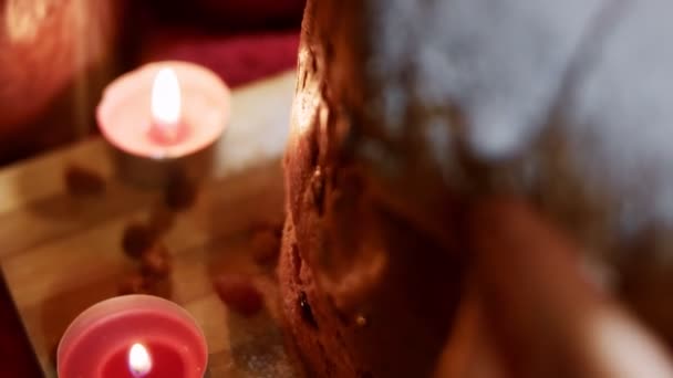 Sucre en poudre sur le dessus de délicieux Panettone de Milan dans une belle atmosphère de bougies. Pâtisseries italiennes traditionnelles pour Noël avec des fruits secs. Tranche de panettone montrée de près. Vidéo 4K — Video