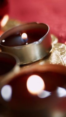 Yanan üç çay mumunun dikey yakın çekimi. Mumlarla güzel bir atmosfer yaratmak. 4K video