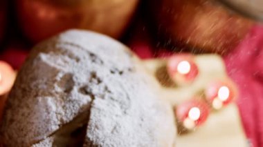 Güzel bir mum atmosferinde lezzetli bir Panettone 'un üzerine pudra şekeri düşer. Noel için geleneksel İtalyan hamur işleri ve kurutulmuş meyveler. Milan 'ın tatlı ekmeği Panettone. 4K video