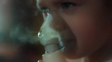 Küçük kız kanepede otururken kompresör spreyiyle solunum yapıyor. Beş yıl oldu. Elinde nebulizör maskesi vardı ve salin buharı soluyordu. 4K video