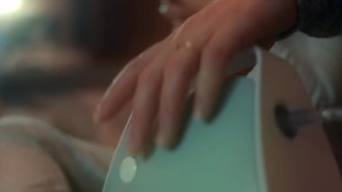 Küçük kız kanepede otururken kompresör spreyiyle solunum yapıyor. Beş yıl oldu. Yüzünde nebulizör maskesiyle salin buharı soluyan bir kız. Anne, kızının evde nefes almasına yardım ediyor.