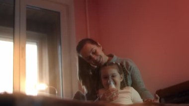 Güzel küçük kız kanepede otururken kompresör spreyiyle solunum yapıyor. Beş yıl oldu. Yüzünde nebulizör maskesiyle salin buharı soluyan bir kız. Anne kızının nefes almasına yardım ediyor.