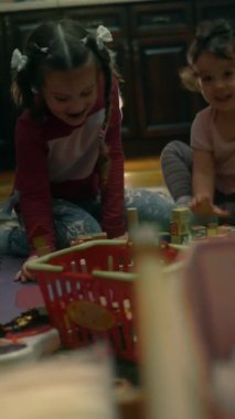 Küçük şirin kız kardeşlerin dikey yakın çekimi birlikte oynuyorlar. Evdeki mutlu kızlar. Komik kız kardeşler oyuncaklarla oynarken eğleniyorlar. 4K video