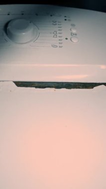 İç mekanda çalışan paslı bir çamaşır makinesinin dikey görüntüsü. Pas sorunu. Çamaşır makinesinin tadilata ihtiyacı var. 4K video