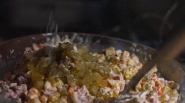 Geleneksel Rus salatası Olivier 'i hazırlıyorum. Yeşil bezelye, salatalık, patates, sosis, havuç, yumurta, mayonez. Tuz ve biberle tatlandırılmış. 4K video