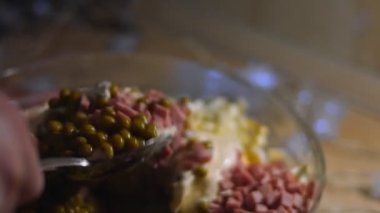 Geleneksel Rus salatası Olivier 'i hazırlıyorum. İçindekileri cam bir kasede karıştırıyorum. Yeşil bezelye, patates, sosis, havuç, yumurta, mayonez. 4K video
