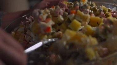 Geleneksel Rus salatası Olivier 'i hazırlıyorum. İçindekileri cam bir kasede karıştırıyorum. Yeşil bezelye, patates, sosis, havuç, yumurta, mayonez. 4K video