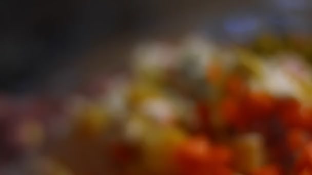 Подготовка русского традиционного салата Оливье. Смешивание ингредиентов в стеклянной миске - зеленый горох, картофель, колбаса, морковь, яйца, майонез. 4К видео. Макровзгляд — стоковое видео
