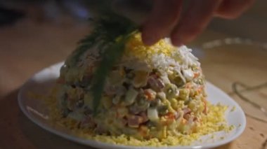 Beyaz tabakta Olivier salatası, rendelenmiş yumurta ve dereotuyla süslenmiş. Geleneksel Yeni Yıl ve Noel Rus salatası. Yakın çekim, 4K video. Sanatsal çekim