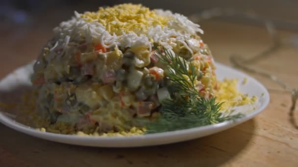 Salade Olivier sur une assiette blanche, décorée d'oeuf râpé et d'aneth. Salade traditionnelle du Nouvel An et de Noël russe. Gros plan, vidéo 4K — Video
