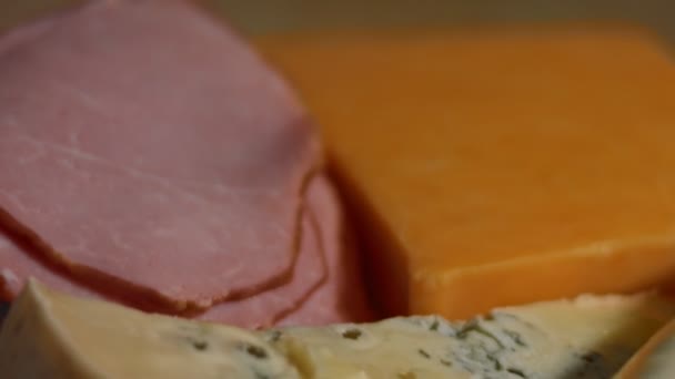 Varios tipos de quesos salados y frescos y jamón de cerdo listo para ser cortado como aperitivo, video 4K. Lento. — Vídeos de Stock