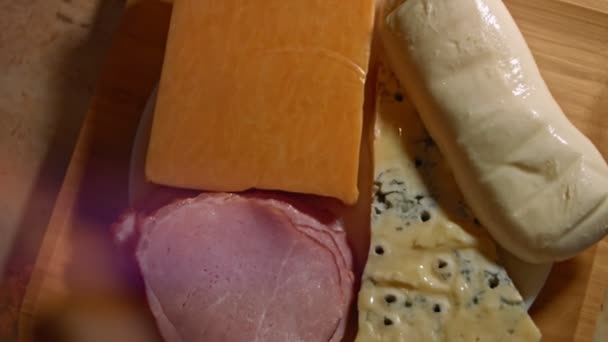Différents types de fromages salés et frais et jambon de porc prêts à être coupés en apéritif, vidéo 4K. Slowmotion, vue de dessus — Video