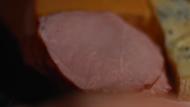 Différents types de fromages salés et frais et jambon de porc prêts à être coupés en entrée et disposés sur un plateau en bois. Vidéo 4K. Tournage artistique, ralenti — Video