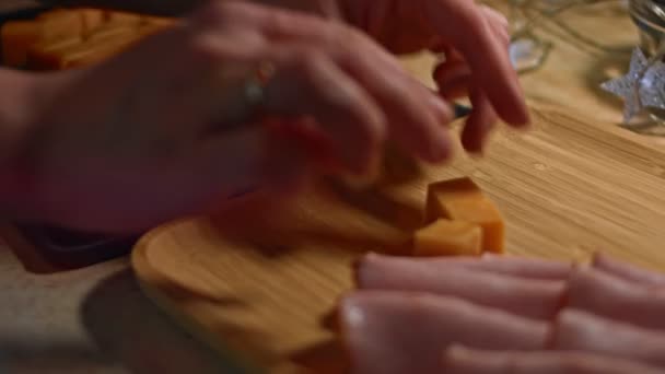 Kostki sera Cheddar są układane na drewnianej tacy jako smaczne i atrakcyjnie wyglądające przystawki. Wideo 4K — Wideo stockowe